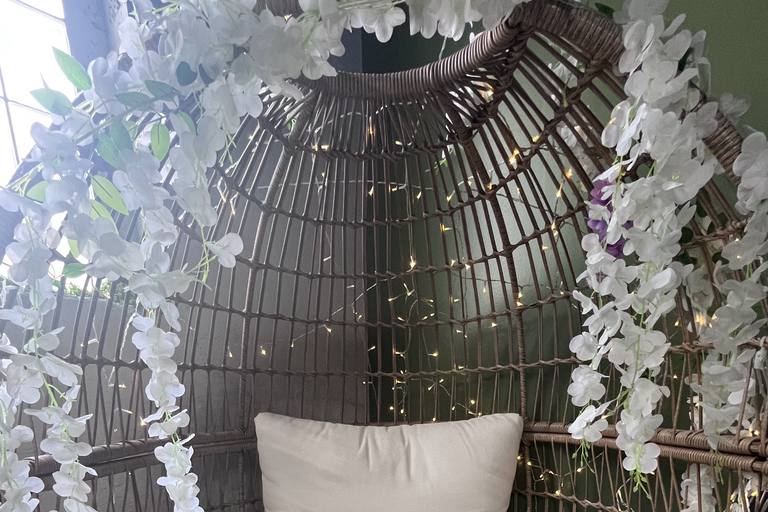A cushioned cocoon chair framed by greenery and string lights.