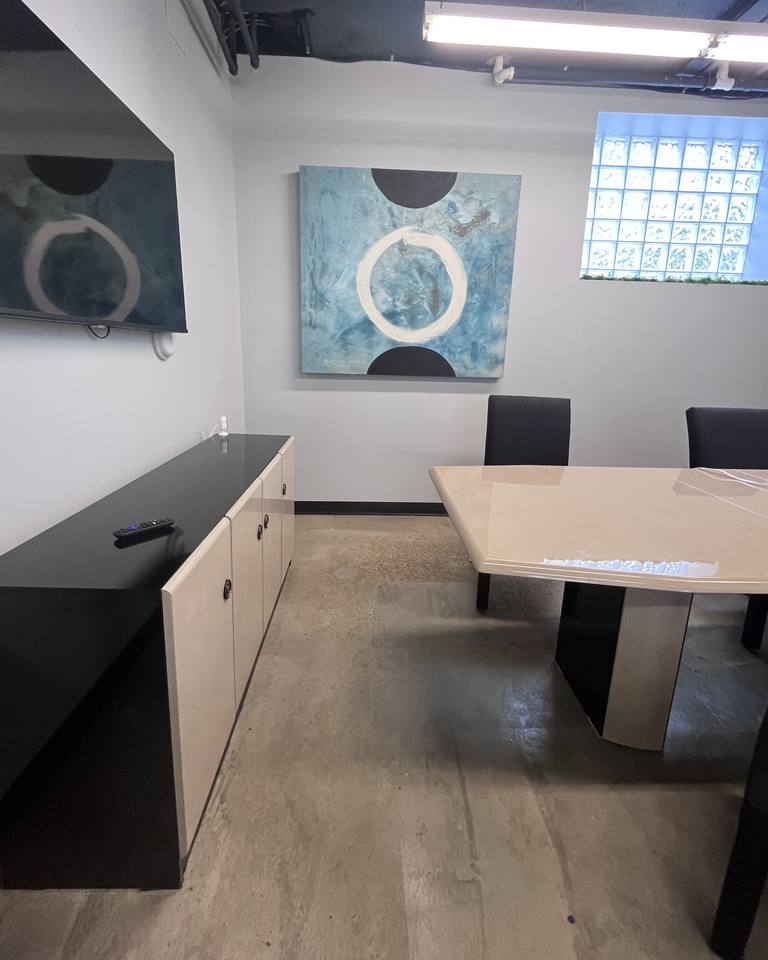 A private conference room with a long table, seating, and original artwork.