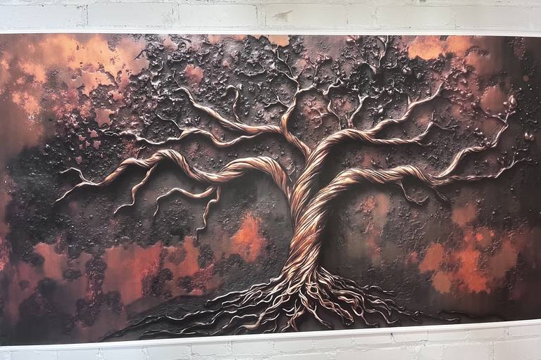 A warm copper tree-of-life relief on white brick in Eden 314's event space.